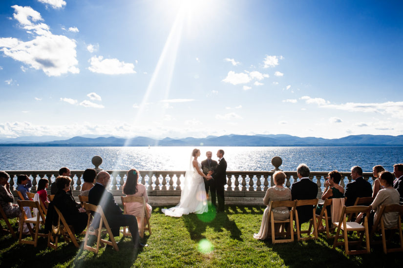 A sunny wedding ceremony on Lake Champlain with mountain views at the Inn at Shelburne Farms;Vermont Wedding;Wedding Ceremony